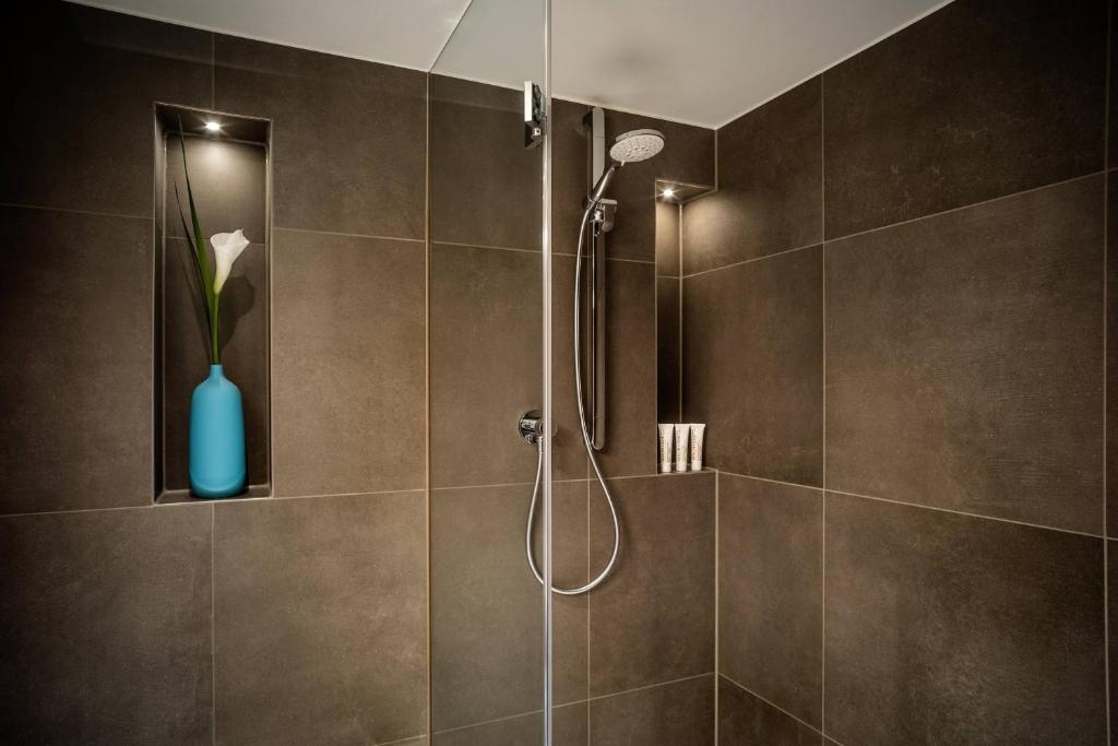 a bathroom with a shower with a blue vase at Le Méridien Munich in Munich