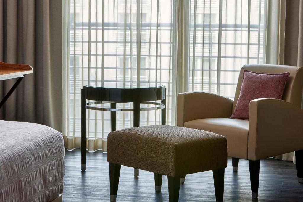 a hotel room with a chair and a table and a window at Le Méridien Munich in Munich