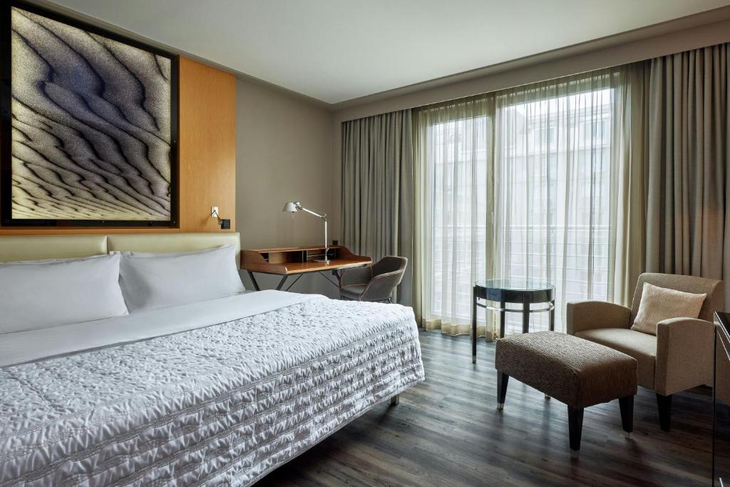 a hotel room with a bed and a desk and a chair at Le Méridien Munich in Munich