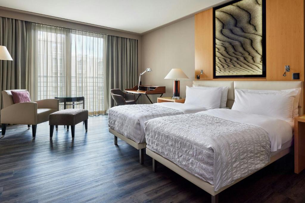 a hotel room with two beds and a desk at Le Méridien Munich in Munich