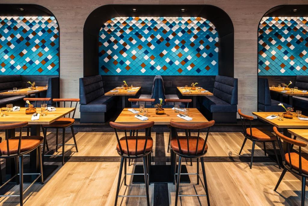 a restaurant with wooden tables and blue booths at Le Méridien Munich in Munich