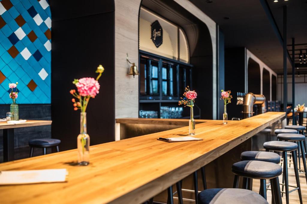 a long wooden bar in a restaurant with stools at Le Méridien Munich in Munich