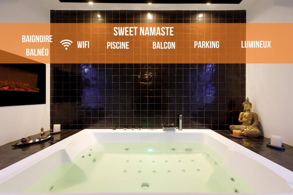a bath tub in a room with black tiles at Sweet Namaste - Host Provence in Mandelieu-la-Napoule