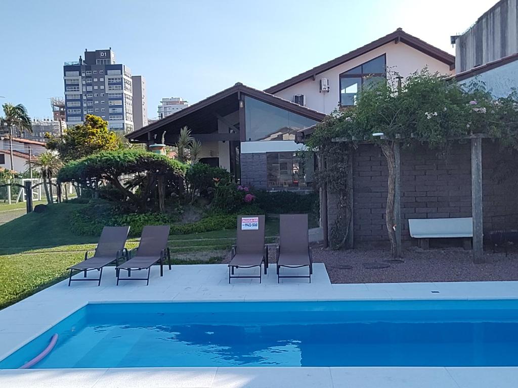 a group of chairs sitting next to a swimming pool at Casarão temporada verão - Propriedade do Hotel Matos in Capão da Canoa