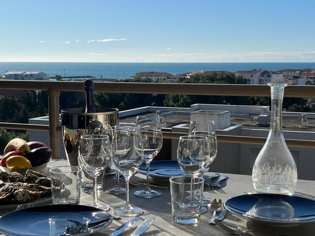 - une table avec des verres à vin et des assiettes sur un balcon dans l'établissement Sète vue mer, secteur des plages, T3 de standing climatisé avec grande terrasse, à Sète