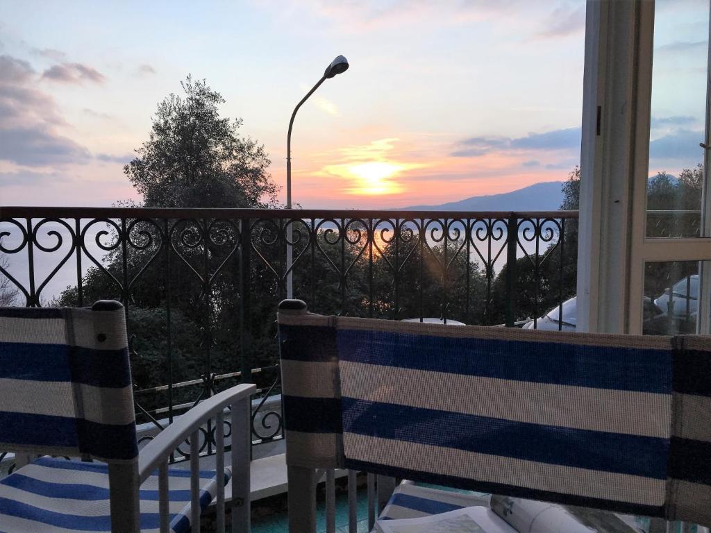 2 sillas en un balcón con puesta de sol en el fondo en House Rouge by Holiday World, en Zoagli