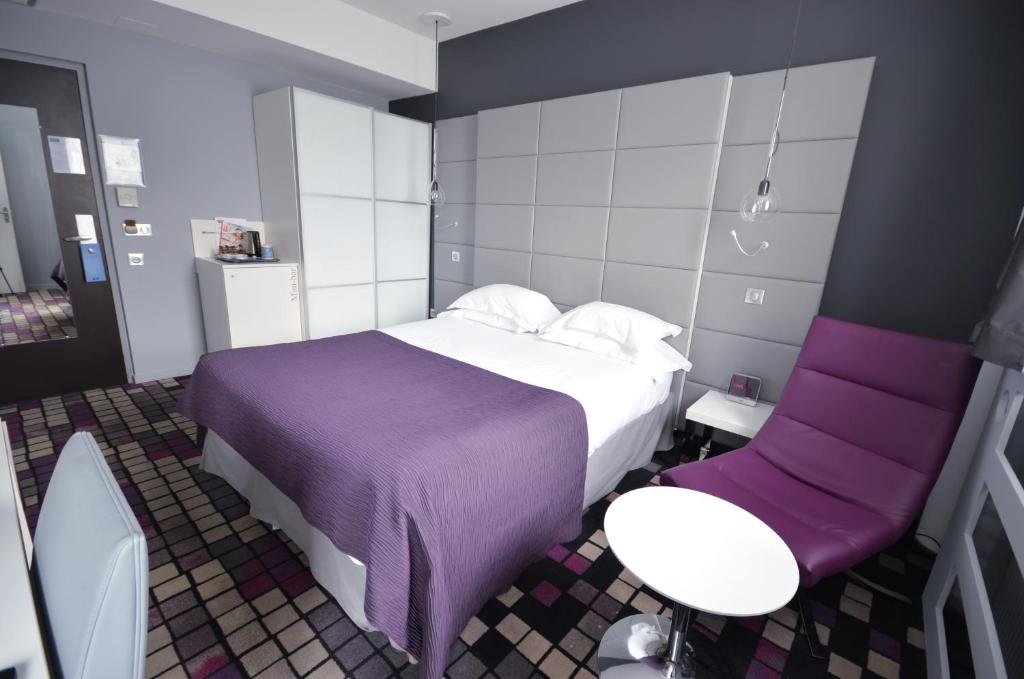 a hotel room with a bed and a chair at Kyriad Prestige Dijon Centre in Dijon