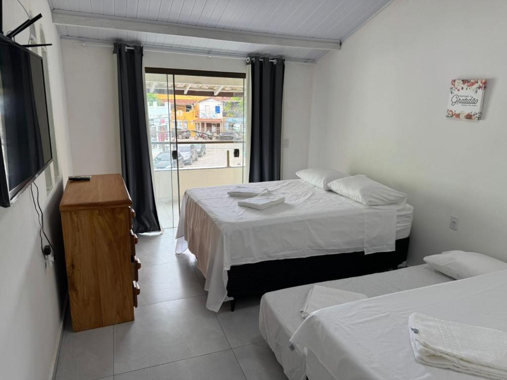a hotel room with two beds and a television at Belas Praias Itacaré 2 in Itacaré