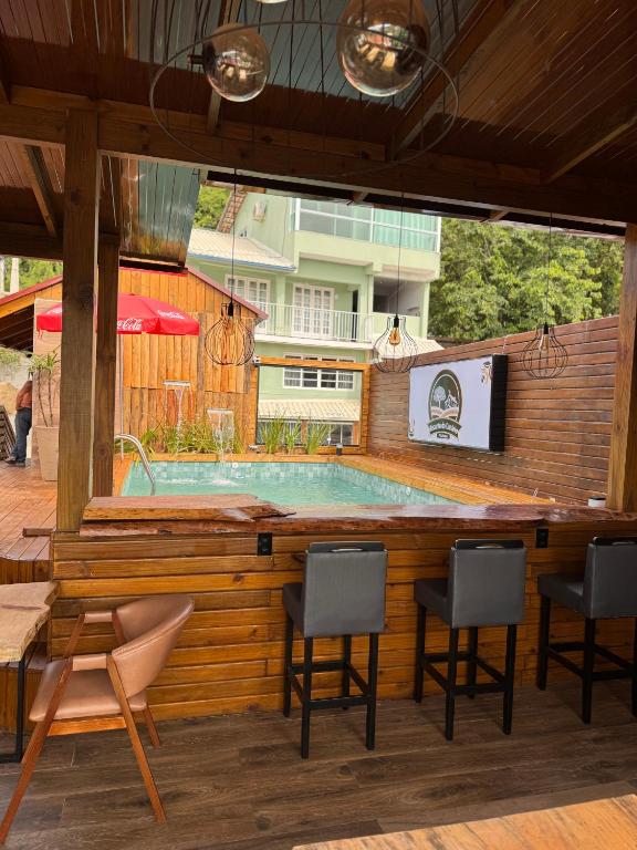 a swimming pool with three chairs and a table at Pousada Recanto do Canário 2 in Governador Celso Ramos