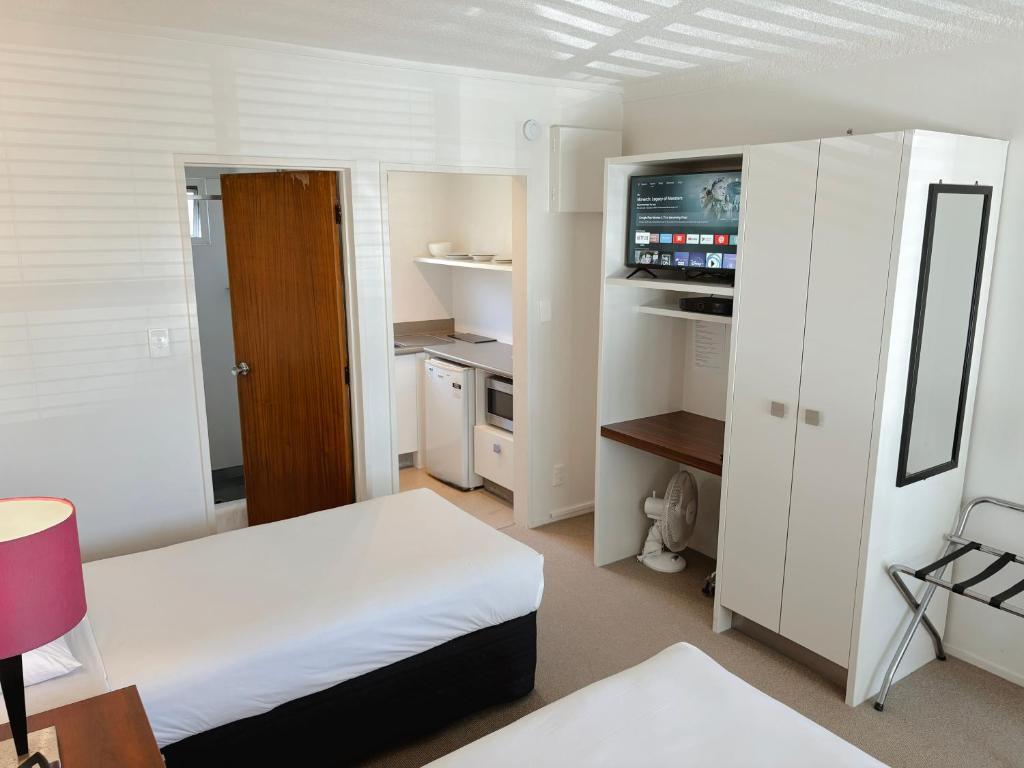 a room with two beds and a television in it at Mt Albert Motor Lodge in Auckland