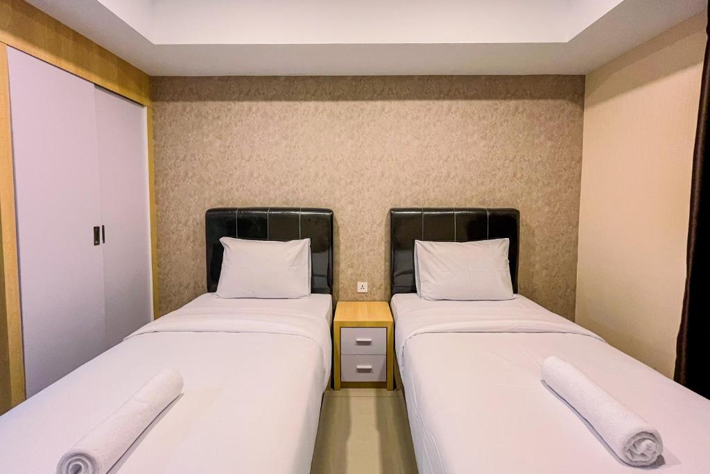 メダンにあるGood Deal and Homey Studio De Prima Apartment By Travelioの小さな部屋に白いシーツが敷かれたベッドが2つ