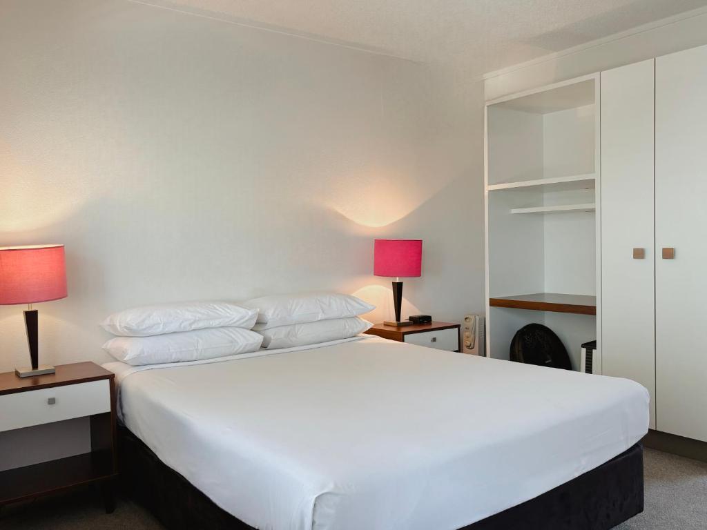 a bedroom with a large white bed with two lamps at Mt Albert Motor Lodge in Auckland