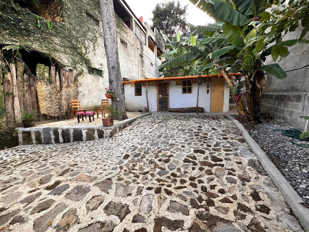 a stone courtyard with a building and a chair at Cabaña del Ciprés interior in San Pedro La Laguna