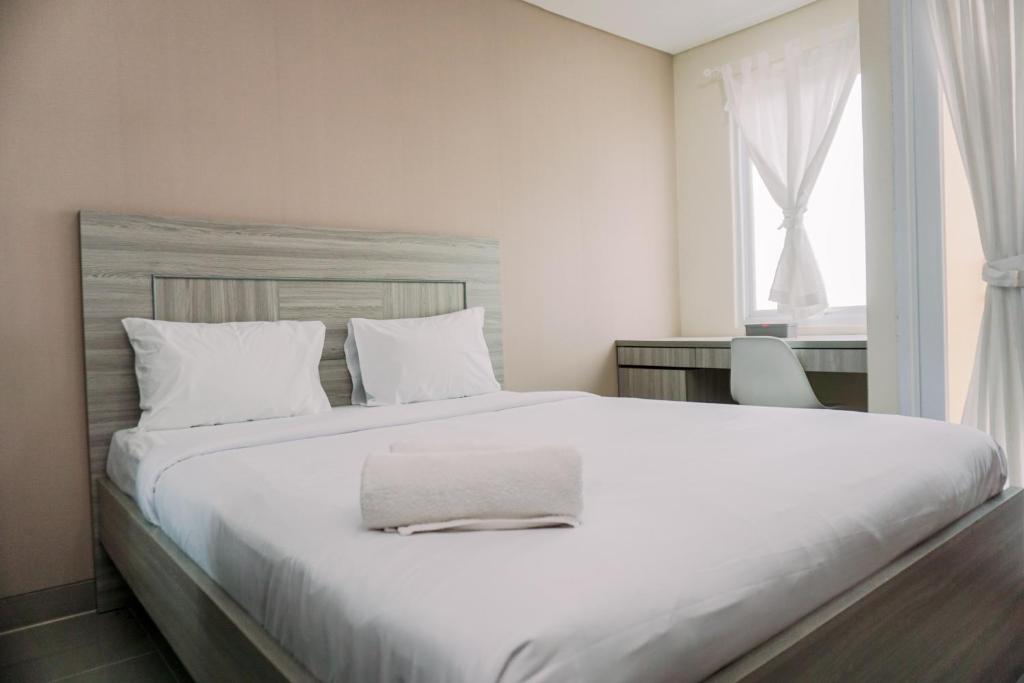 タンゲランにあるSimply and Comfortable Studio Apartment B Residence By Travelioの窓のある大きな白いベッドのある寝室