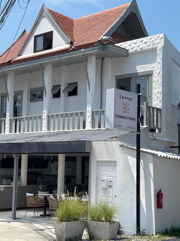 苏梅岛Coffee Connextions Cafe & Rooms的一座白色的房子，前面有一块牌子