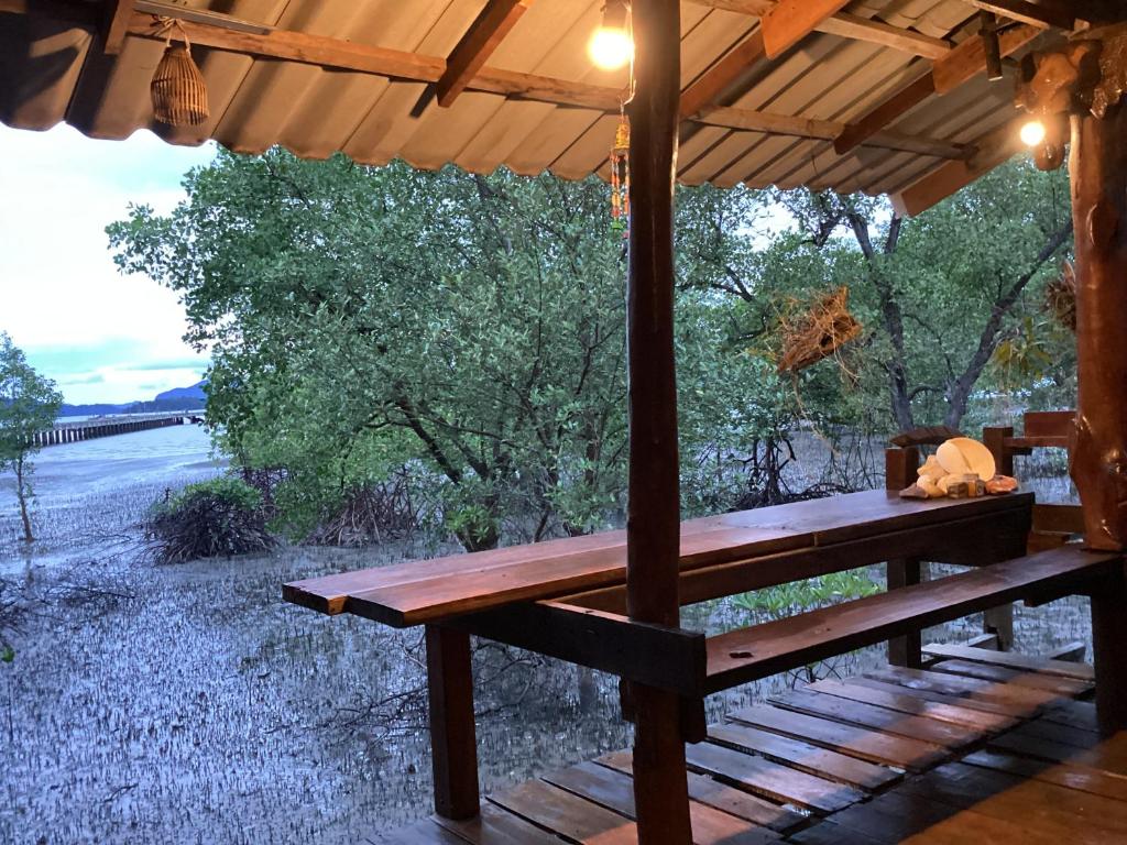 a wooden bench under a pavilion with a view of a river at Banpoo in Ko Yao Noi