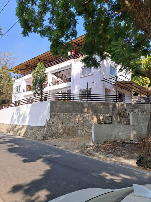 a white house on the side of a street at Johaar Retreat, Bhimtal in Bhowāli