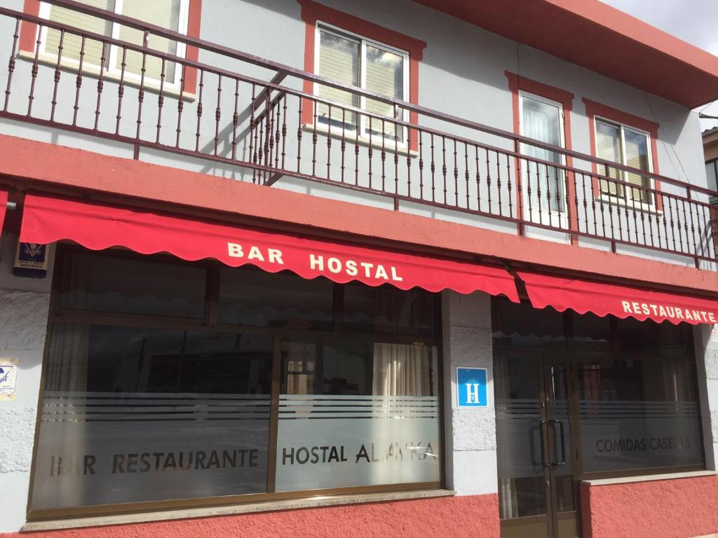 um hospital-bar com um toldo vermelho num edifício em Hostal Alayka em Calvarrasa de Abajo