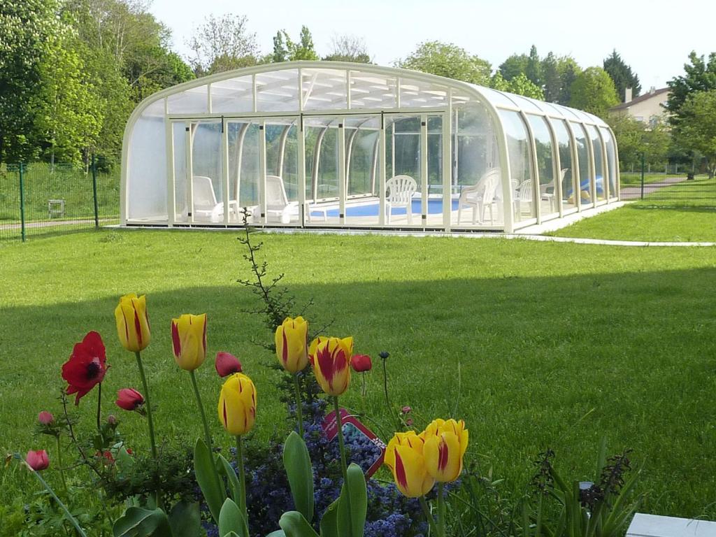 uma estufa num parque com flores na relva em La Grimodière Gîte em Ranville