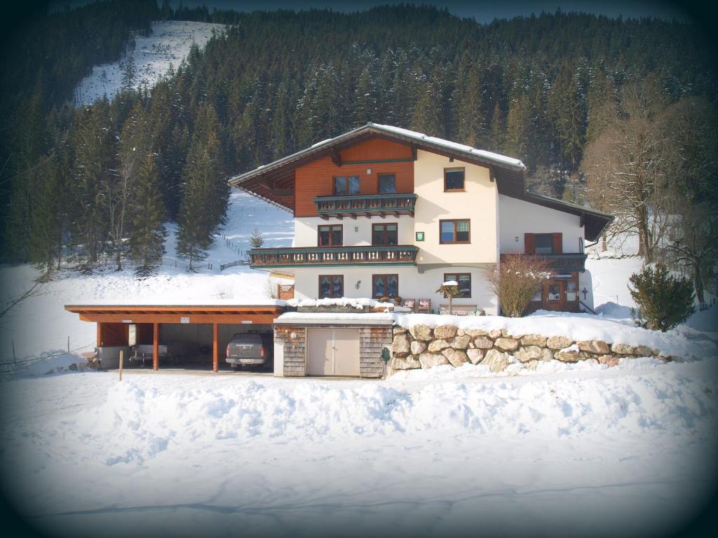 ein großes Haus im Schnee vor einem Berg in der Unterkunft Frühstückspension Pachler in Gosau