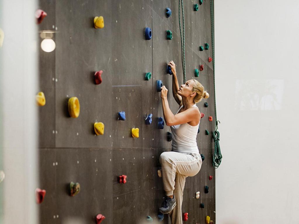 a woman is climbing a rock wall at Sun Gardens Dubrovnik in Dubrovnik