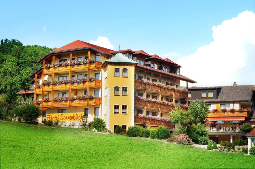 a large yellow building with balconies on a green field at Hotel Sonnenblick in Schwabthal