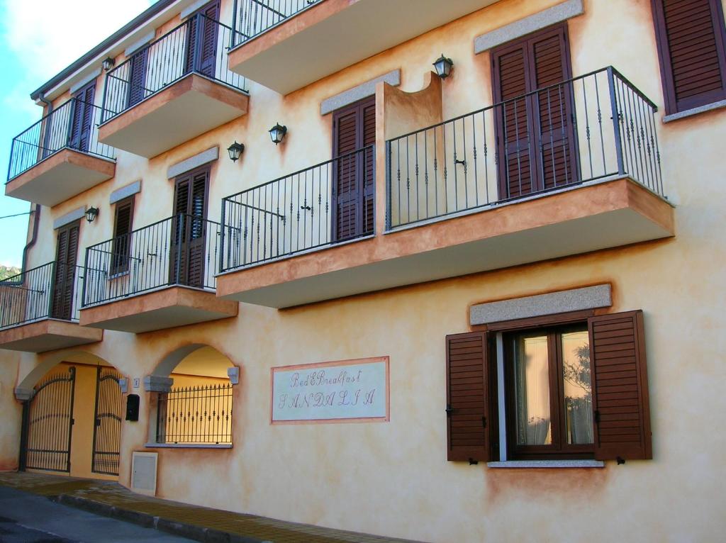 a building with balconies and a sign on it at Hotel Bed Sandalia in Badesi