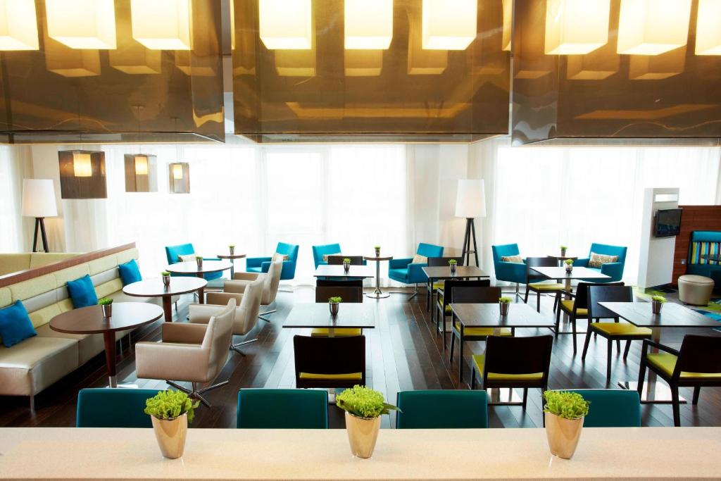 a restaurant with tables and chairs and blue chairs at Courtyard by Marriott Aberdeen Airport in Dyce