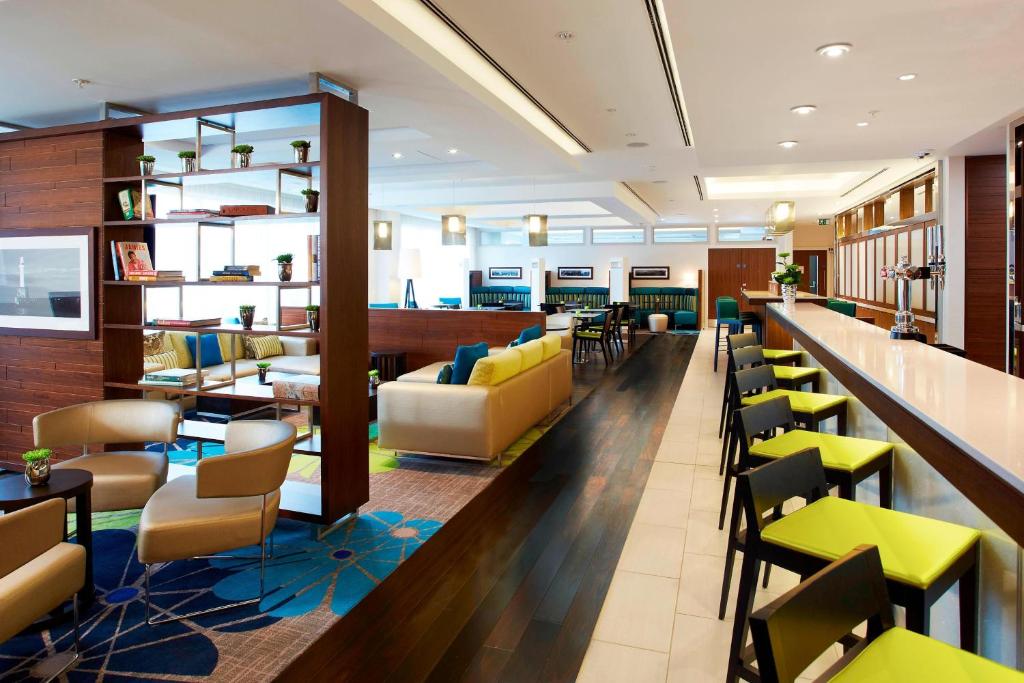 a restaurant with a bar with yellow and blue chairs at Courtyard by Marriott Aberdeen Airport in Dyce