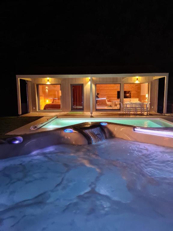 - une piscine la nuit avec une maison en arrière-plan dans l'établissement Le Cottage des Cerisiers, à Saint-Paul-en-Cornillon