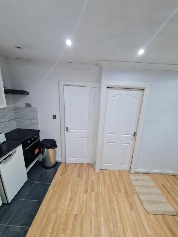 a kitchen with two white doors and a wooden floor at Garden house in Tilbury