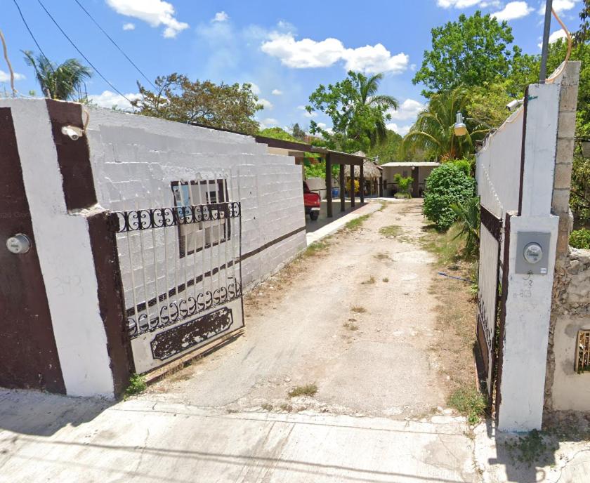 a dirt road with a fence and a building at Casa de reyes in Tizimín