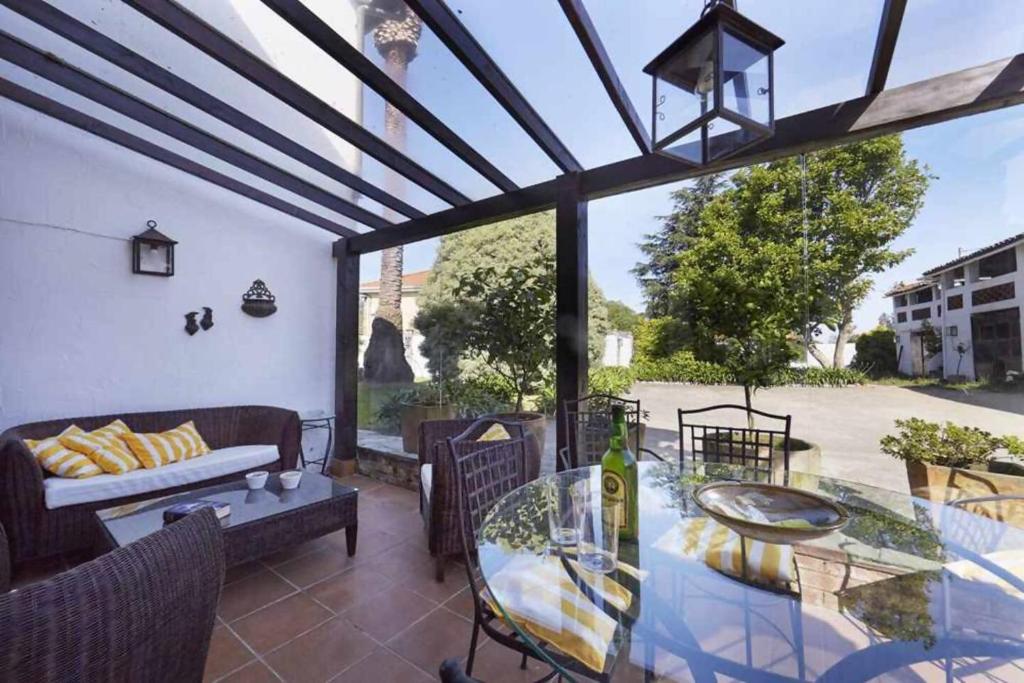a patio with a glass table and a couch at Casa La Palomba in Cudillero