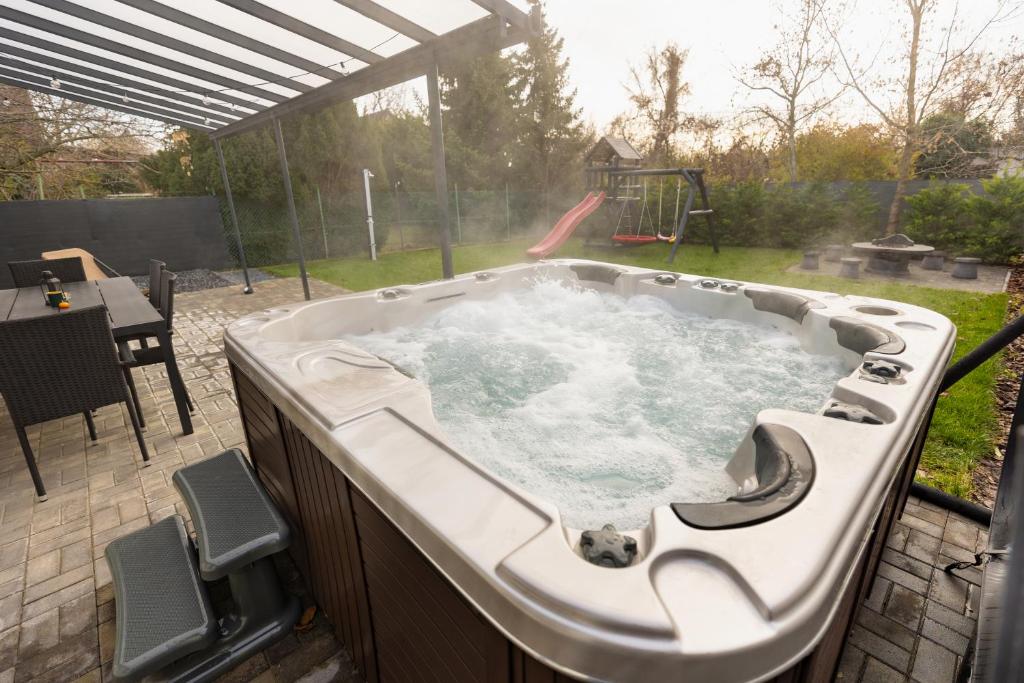 a hot tub in a backyard with a playground at Dream Apartman Aliga in Balatonvilágos