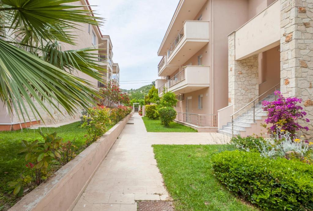 a walkway between two buildings with plants and flowers at Icon Deluxe accommodation in Pefkochori