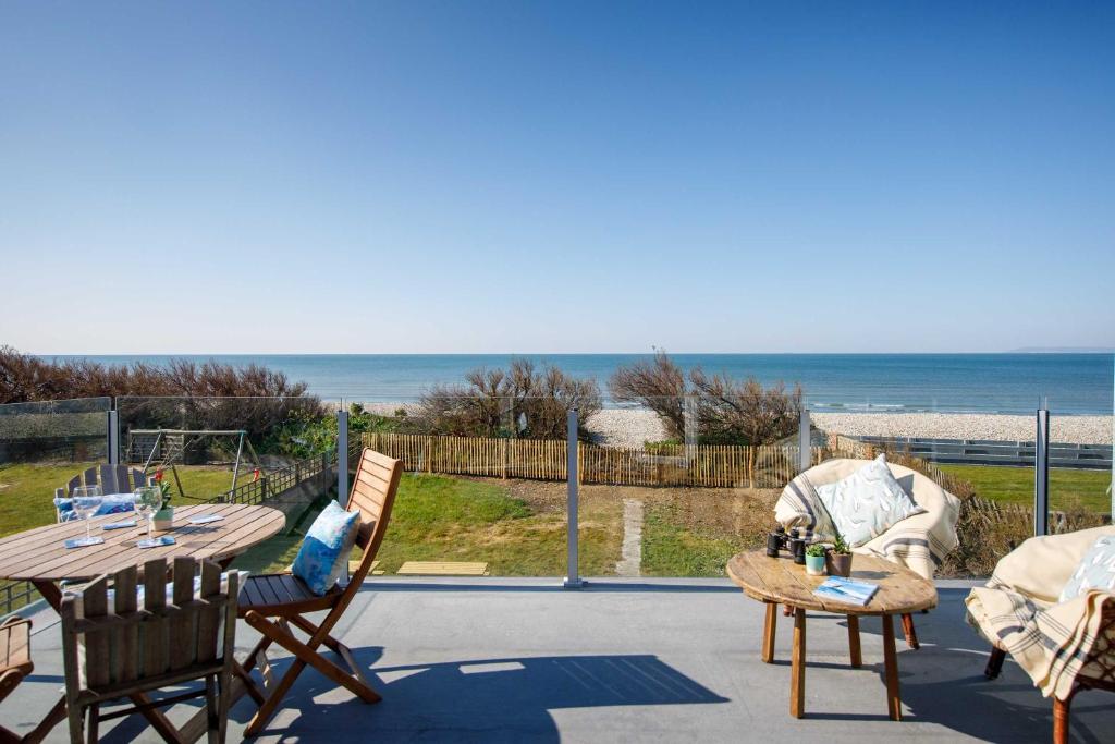 eine Terrasse mit Tisch und Stühlen und dem Meer in der Unterkunft Bright & Dreamy On the Beach Garden & Balcony in Bracklesham Bay