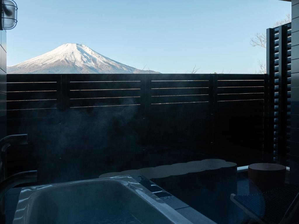 a bath tub with a snow covered mountain in the background at Mt Fuji View and Private Sauna Ryokan Shizuku in Yamanakako