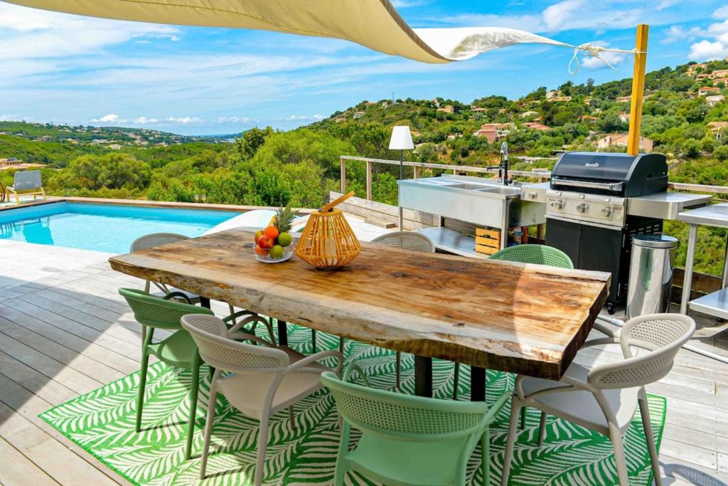 a wooden table and chairs on a patio with a pool at Sandrine - Villa Terrace Pool - by TGB in Pietrosella