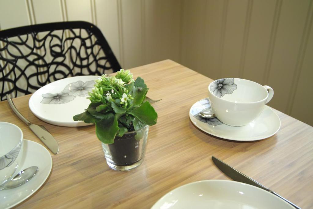 a wooden table with plates and a cup and a plant at Bed &amp; Breakfast De Kleine Magnolia in Tessenderlo