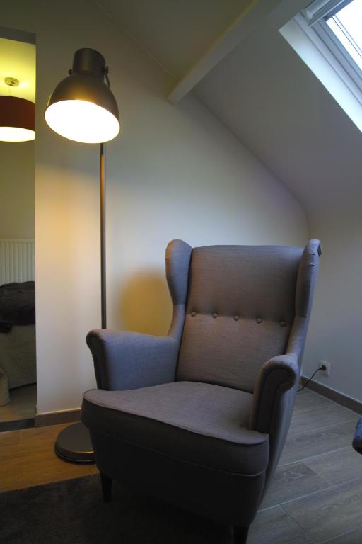 a living room with a chair and a lamp at Bed &amp; Breakfast De Kleine Magnolia in Tessenderlo