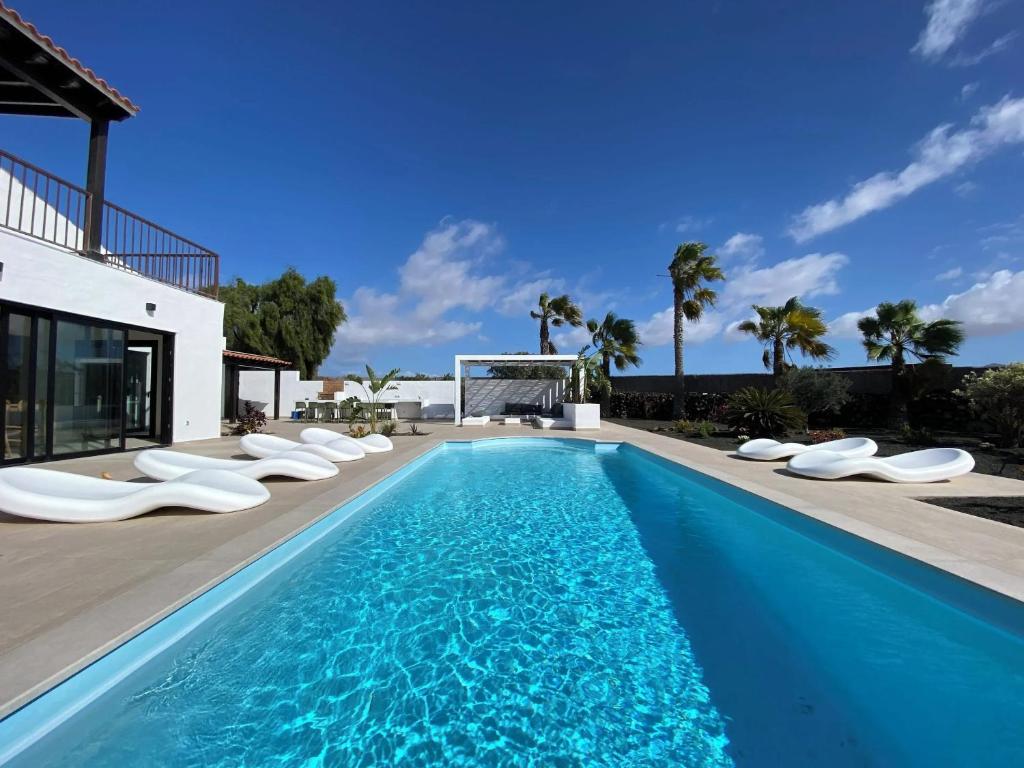 a swimming pool with chaise lounge chairs next to a house at Modern villa in Lajares with private pool in La Oliva