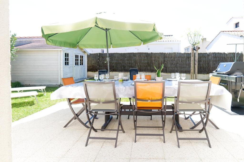 une table avec des chaises et un parasol sur une terrasse dans l'établissement Maison au calme, proche océan, Les Sables 6 personnes, à Les Sables-dʼOlonne