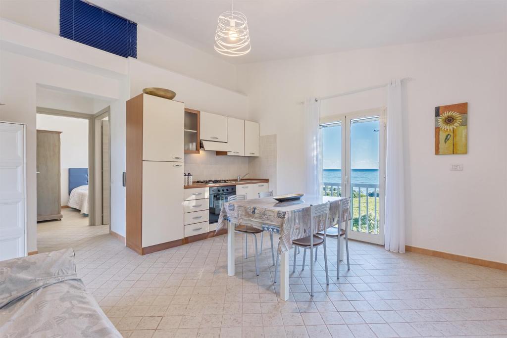 a white kitchen with a table and a view of the ocean at Casa Mulas in Tertenìa