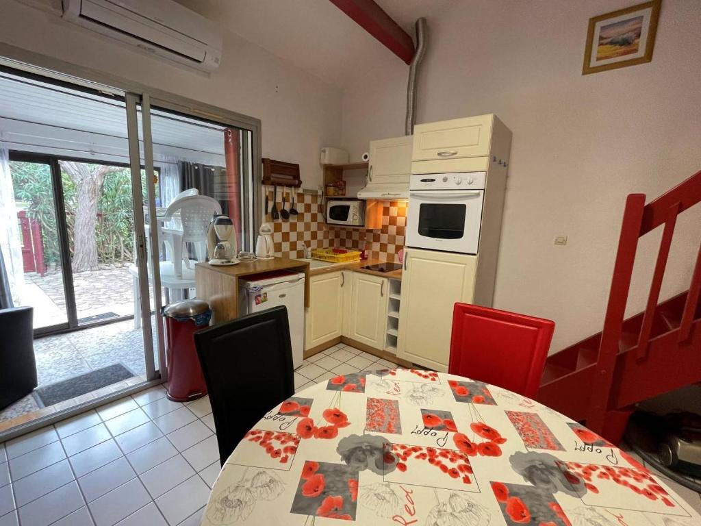 Il comprend une cuisine avec une table, des chaises rouges et une table. dans l'établissement Maison 2 pièces mezzanine 6 couchages SC105-019, à Saint Cyprien Plage