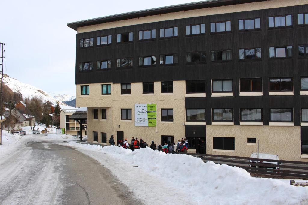 Un groupe de personnes debout dans la neige devant un bâtiment dans l'établissement Auberge de Jeunesse - Les Carlines I, à Vars