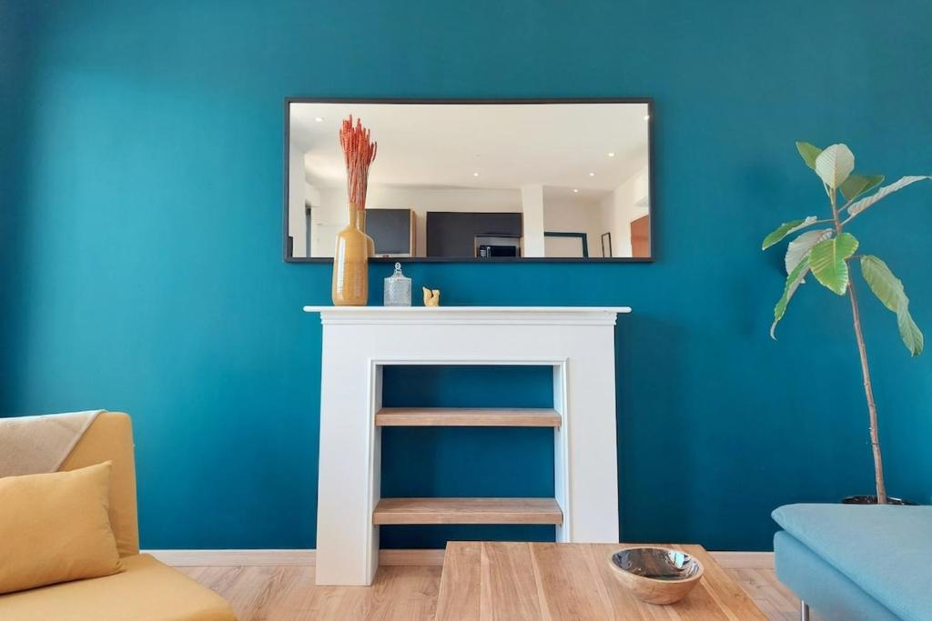 d'un miroir au-dessus d'une cheminée dans un salon aux murs bleus. dans l'établissement Marlene - Terrace Free Parking - by TGB, à Ajaccio