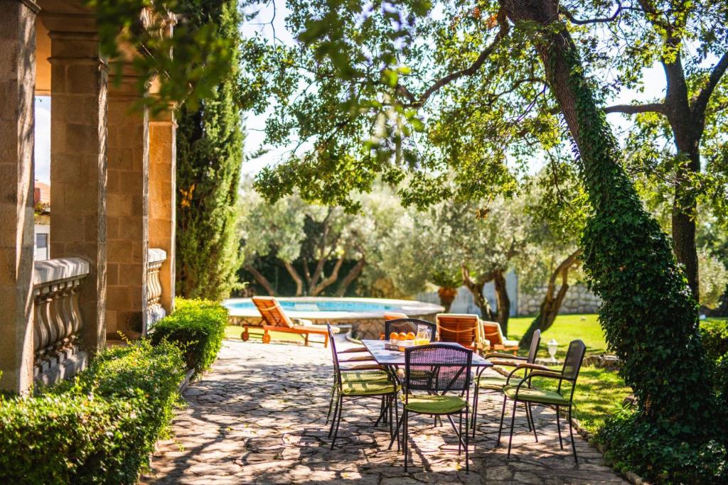 a patio with a table and chairs and a pool at Garden Oasis Pool Villa in Čilipi