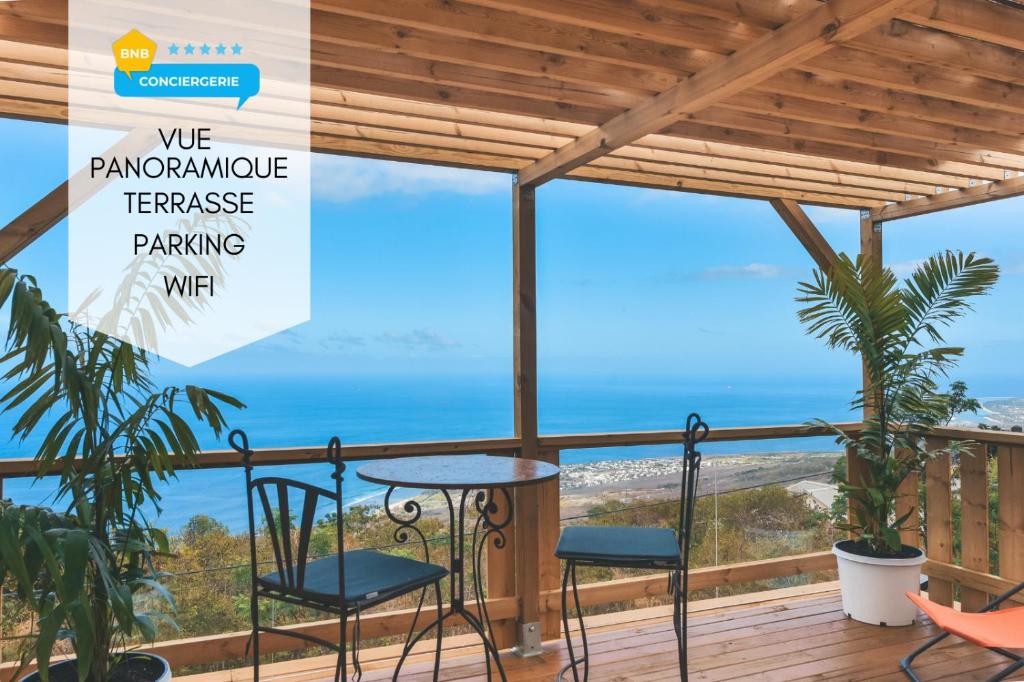 a balcony with a table and chairs and the ocean at OISEAUX DU PARADIS - Bungalow 2 voyageurs in Saint-Leu