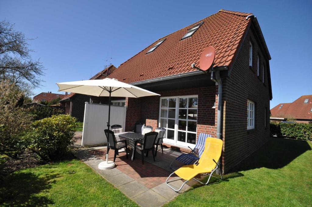 a patio with a table and chairs and an umbrella at Nr 96 - Ferienhaus Uferstraße in Carolinensiel