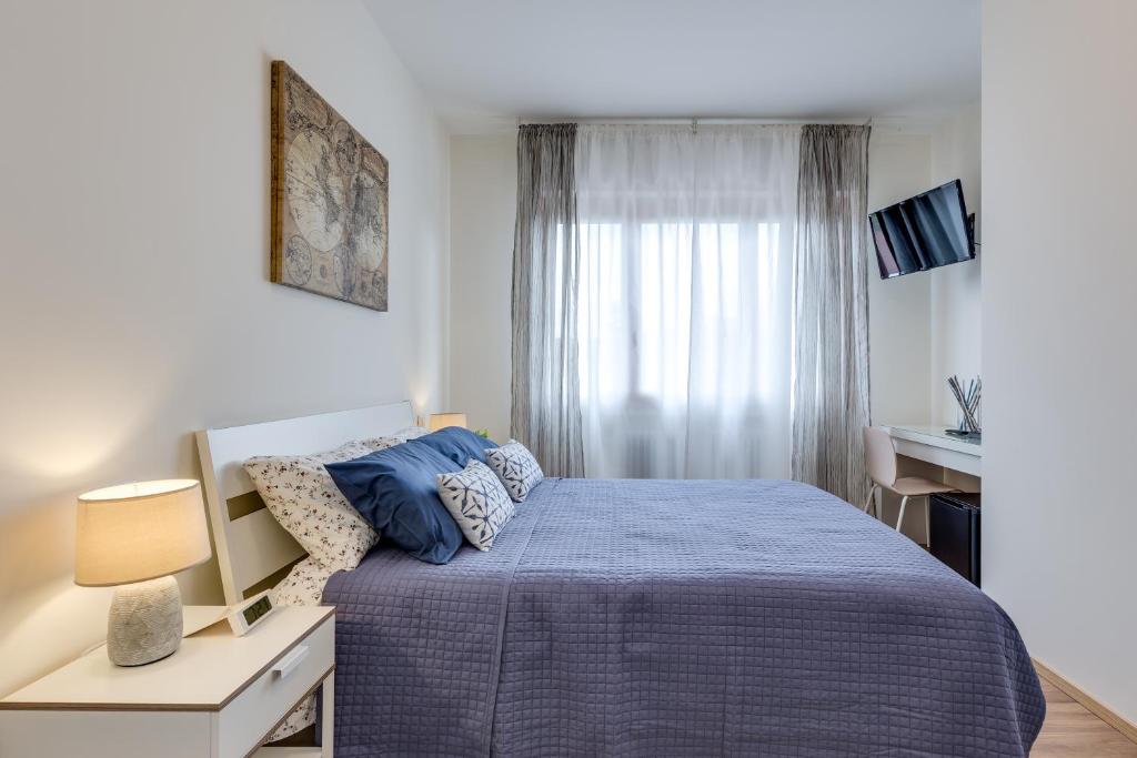 a bedroom with a blue bed and a window at Rooms Vidar Train Station in Marghera